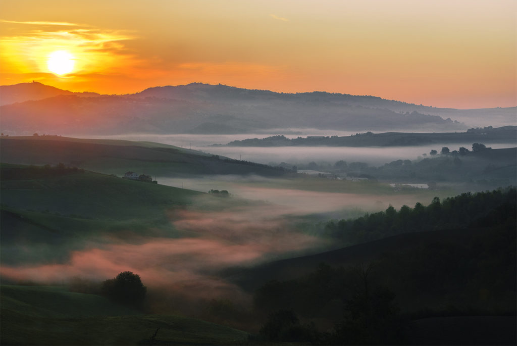 Sole che sorge sui colli di Urbino, nebbia e cielo arancione