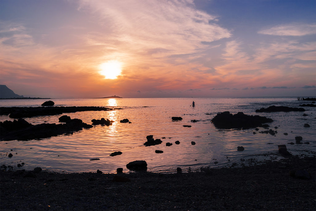 Sole che tramonta sul mare in Sicilia, uomo che rema