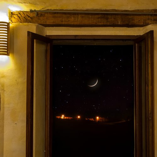 Finestra che si affaccia un panorama notturno, mezza luna e stelle nel cielo nero